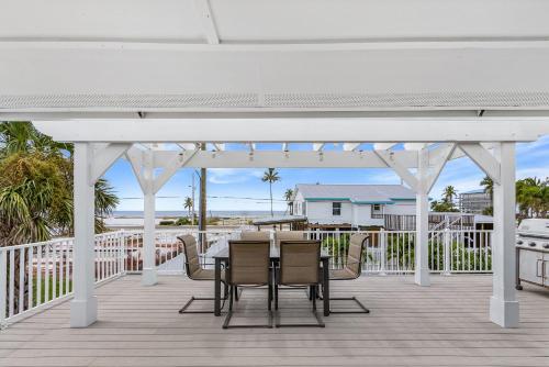 a white pergola on a deck with a table and chairs at Boating Enthusiasts, Walk to the Beach, Heated Pool - The Corner cottage - Roelens in Fort Myers Beach