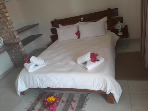 a white bed with towels and flowers on it at Farmhouse Boutique Backyard Rooms in Outjo