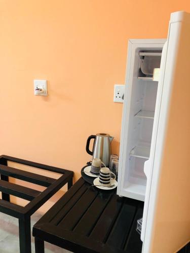 an open refrigerator with a tea kettle on a table at Farmhouse Boutique Backyard Rooms in Outjo