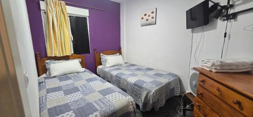 a room with two beds and a dresser and a tv at Rooms Plaza hierro in San Bartolomé de Tirajana