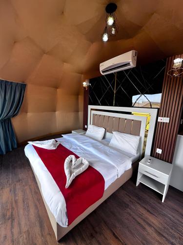 a bedroom with a large white bed with a red blanket at Catalina Luxury rum camp in Wadi Rum