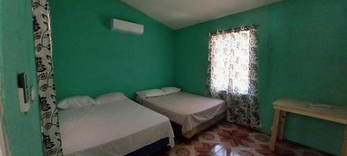 a green room with two beds and a window at Rancho Carmen in El Garitón
