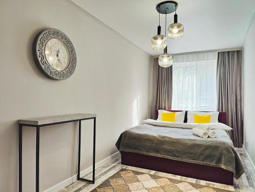 une chambre avec un lit et une horloge au mur dans l'établissement Арбат в Золотом квадрате двухкомнатная стильная в центре 25, à Almaty