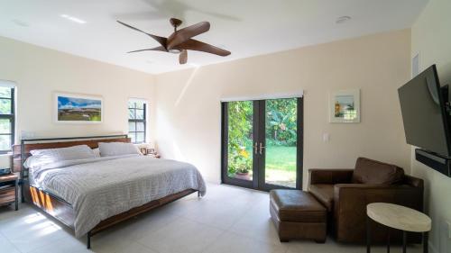 a bedroom with a bed and a chair and a ceiling fan at Villa Viscayne - Miami Modern Luxury with Pool & Spa in Biscayne Park