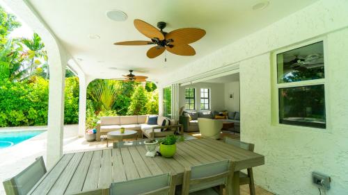 a living room with a wooden table and a ceiling fan at Villa Viscayne - Miami Modern Luxury with Pool & Spa in Biscayne Park