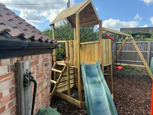 a wooden play set with a slide and a play house at 5 Bed in Blofield oc-s33037 in Blofield