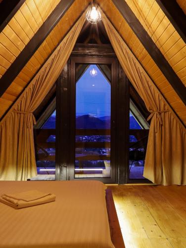 a bedroom with a bed and a large window at Nale Luxury Chalet in Bratunac