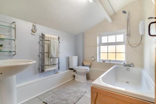 a bathroom with a tub and a toilet and a sink at Valentine Cottage in Snape
