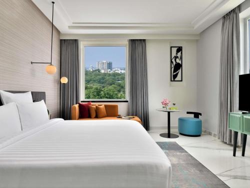 a bedroom with a large white bed and a large window at Novotel Jodhpur ITI Circle in Jodhpur