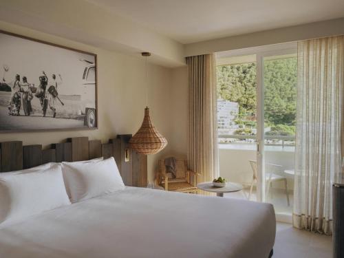 a bedroom with a white bed and a large window at Hyde Ibiza in Cala Llonga