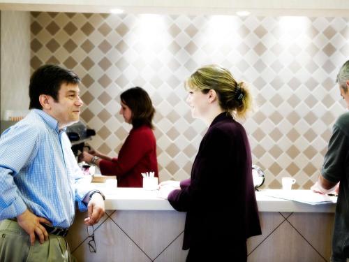 a man and a woman standing at a counter at Mercure Szekesfehervar Magyar Kiraly in Székesfehérvár