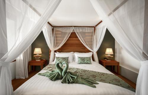 a bedroom with a bed with a green ribbon on it at Phandara Luxury Pool Villas in Koh Tao