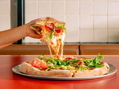 a person eating a slice of pizza on a table at Mantra South Bank Brisbane in Brisbane