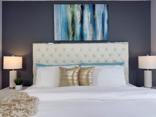 a bedroom with a white bed with a painting above it at Near Disney, Private South Facing Pool, Star Wars Arcade Theater, 3 King Beds in Orlando