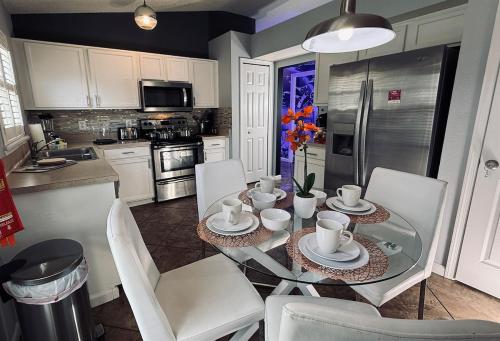 a kitchen with a glass table and white chairs at Near Disney, Private South Facing Pool, Star Wars Arcade Theater, 3 King Beds in Orlando