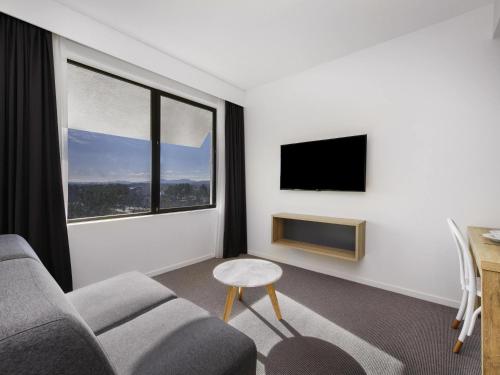 a living room with a couch and a window at Mantra MacArthur Hotel in Canberra