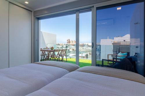 ein Schlafzimmer mit einem Bett und einem großen Fenster in der Unterkunft Luxury Beach Terrace Loft in Las Palmas de Gran Canaria
