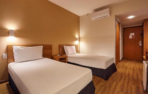 a hotel room with two beds and a door at Hotel Nacional Inn Bauru in Bauru