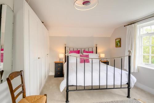 ein Schlafzimmer mit einem Bett mit rosa Kissen in der Unterkunft Riverside Cottage in Snape