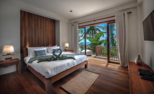 1 dormitorio con 1 cama y vistas a un balcón en Phandara Luxury Pool Villas, en Ko Tao