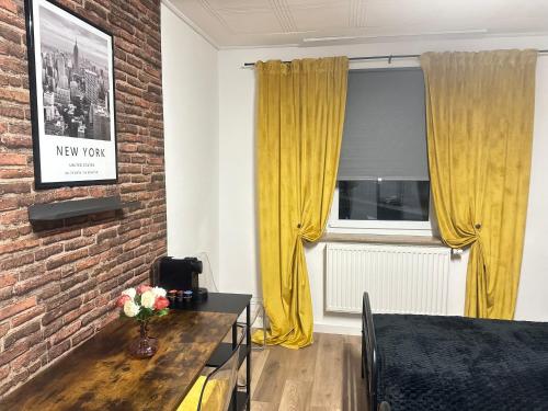 a living room with a brick wall and yellow curtains at Gästezimmer New York im Werkmotel in Winhöring