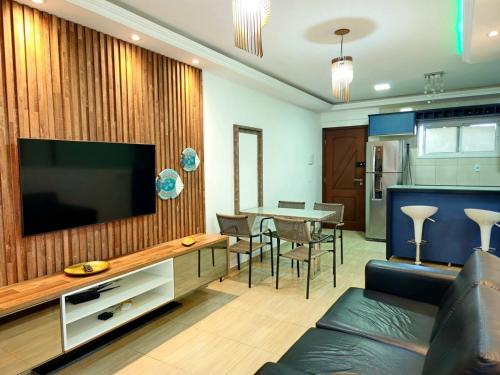 a living room with a television and a table with chairs at Elegance Residences Cumbuco in Caucaia
