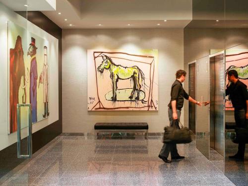 a man looking at a painting of a horse on the wall at The Cullen Melbourne - Art Series in Melbourne
