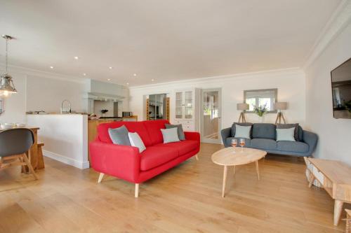 Una sala de estar con un sofá rojo y una mesa. en Denbury House, en Bodham