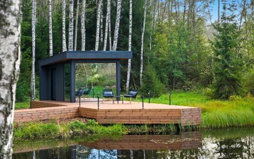 a house with two chairs sitting on a platform over a body of water at ForestSpa in Pedajamäe