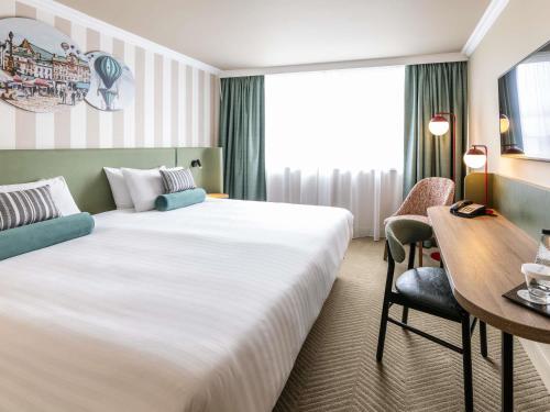 a hotel room with a large bed and a desk at Mercure Northampton in Northampton