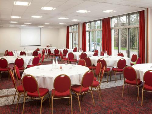 a conference room with white tables and red chairs at Mercure Northampton in Northampton