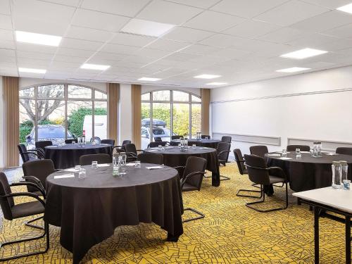 a conference room with tables and chairs and a whiteboard at Mercure Northampton in Northampton