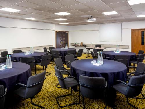 a conference room with blue tables and chairs and a screen at Mercure Northampton in Northampton