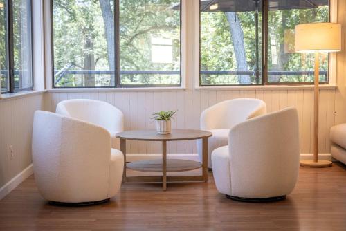 a room with white chairs and a table and windows at Lake Access Pool Loungers Fire Pit Grill in McQueeney