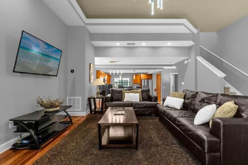 a living room with a leather couch and a table at Cozy & Elegant 4BR Enchanted Townhouse - 1 Mile to Disney with Resort Pool, Gym, & Jacuzzi in Orlando