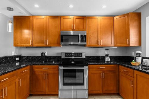 a kitchen with wooden cabinets and stainless steel appliances at Cozy & Elegant 4BR Enchanted Townhouse - 1 Mile to Disney with Resort Pool, Gym, & Jacuzzi in Orlando