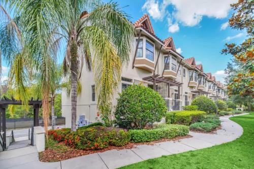 a house with palm trees and a sidewalk at Cozy & Elegant 4BR Enchanted Townhouse - 1 Mile to Disney with Resort Pool, Gym, & Jacuzzi in Orlando