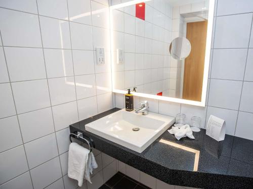 a white bathroom with a sink and a mirror at Mercure Thurrock Stifford Hall in Grays Thurrock