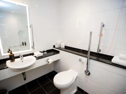 a white bathroom with a toilet and a sink at Mercure Thurrock Stifford Hall in Grays Thurrock
