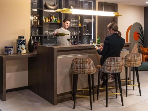 a man and a woman sitting at a bar at ibis Styles Saint-Quentin in Saint-Quentin