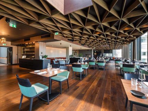 a restaurant with wooden ceilings and tables and chairs at Movenpick Hotel Tallinn in Tallinn