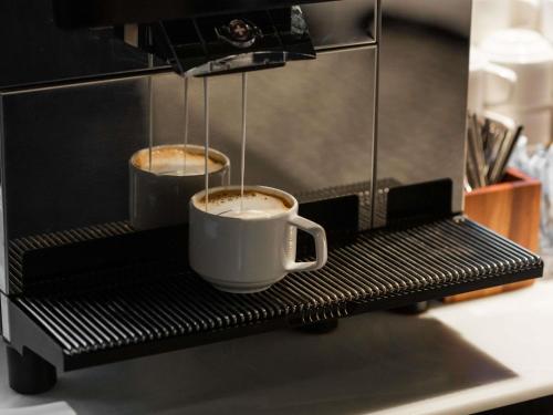 two cups of coffee on a coffee machine at Movenpick Hotel Tallinn in Tallinn