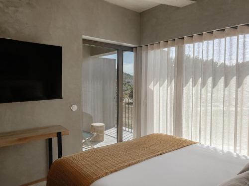 una camera da letto con un letto, una televisione e un balcone di Soadro do Zêzere - Hotel Rural e Restaurante a Valhelhas