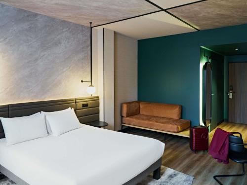 a bedroom with a white bed and a chair at Novotel Rouen Centre Cathédrale in Rouen