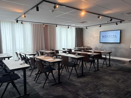 a dining room with tables and chairs and a screen at Novotel Rouen Centre Cathédrale in Rouen