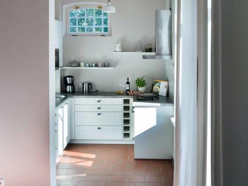 a white kitchen with white cabinets and a window at Gut Petersdorf Lensahn - ideal für Familien und Hunde - mit Kamin, Parkblick, Terrasse und eingezäuntem Garten in Lensahn