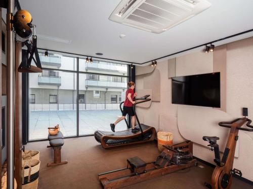 a woman running on a treadmill in a gym at Novotel Rouen Centre Cathédrale in Rouen