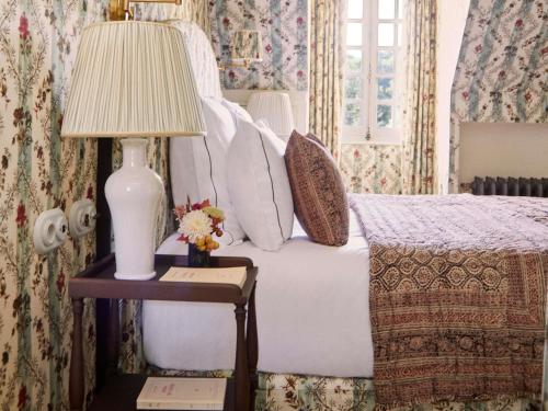 a bedroom with a bed with a lamp on a table at Abbaye Des Vaux De Cernay in Cernay-la-Ville