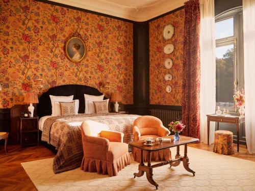 a bedroom with a bed and two chairs and a table at Abbaye Des Vaux De Cernay in Cernay-la-Ville