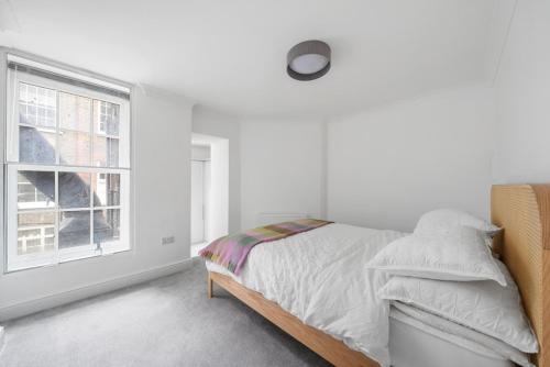 a white bedroom with a bed and a window at Modern Apartment Charing Cross - Aircon in London